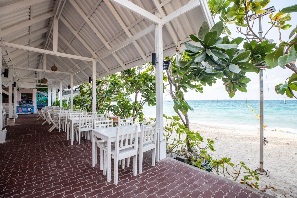 ร้านอาหารบนชายหาดพร้อมโต๊ะและเก้าอี้สีขาว ที่พักหาดนวล