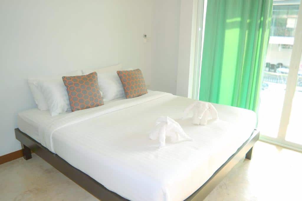 เตียงสีขาวในห้องที่มีผ้าม่านสีเขียว มอบบรรยากาศการพักผ่อนริมชายฝั่งอันงดงาม ที่พักติดทะเลชุมพร