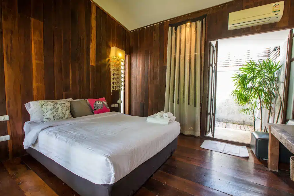 ห้องนอนแสนสบายพร้อมผนังไม้เรียบง่ายและพื้นไม้อบอุ่น ที่พักอัมพวาริมน้ำ
