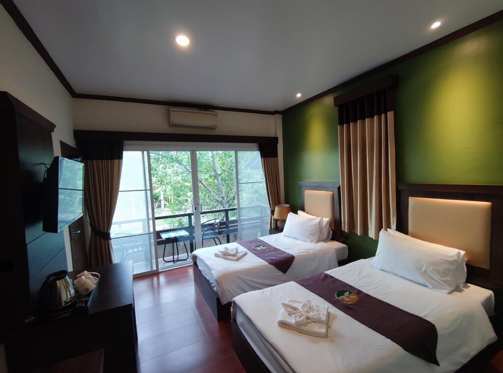 เตียงสองเตียงในห้องที่มีผนังสีเขียว โรงแรมอัมพวา