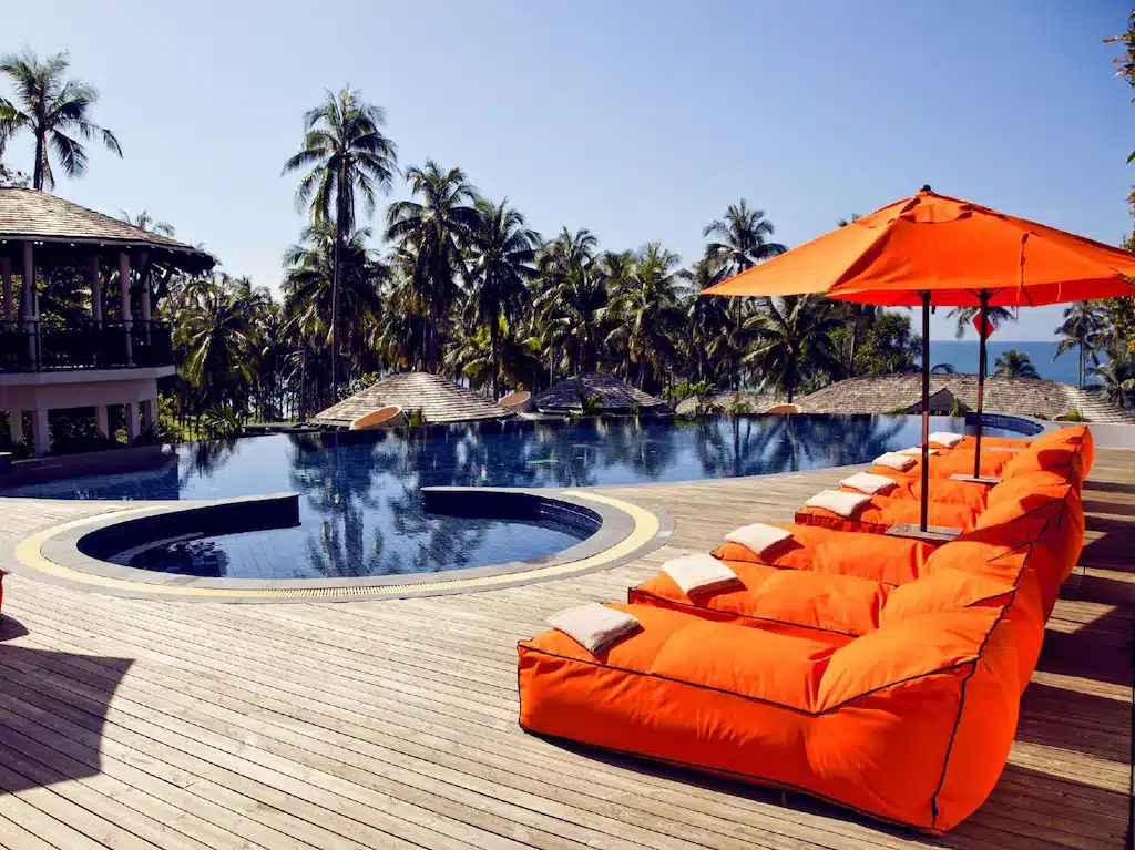 สระว่ายน้ำพร้อมเบาะรองนั่งสีส้มและร่มในเที่ยวราชบุรี ที่พักเกาะกูด