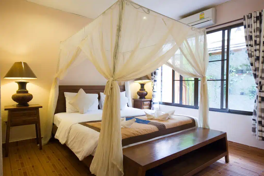 เตียงสี่เสาในห้องที่มีพื้นไม้ เหมาะสำหรับการเข้าพักที่สะดวกสบาย รีสอร์ทเชียงใหม่