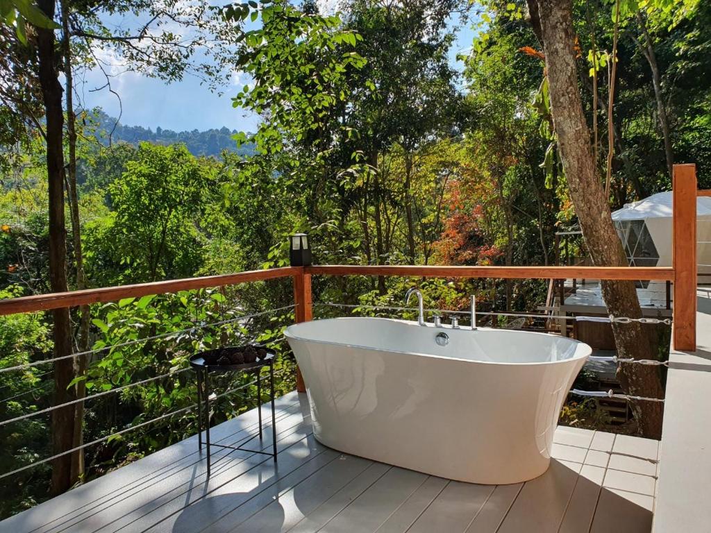 อ่างอาบน้ำสีขาวตั้งอยู่บนดาดฟ้าที่มองเห็นป่าอันงดงามที่ปราสาทแม่กำปอง ที่พักแม่กำปอง