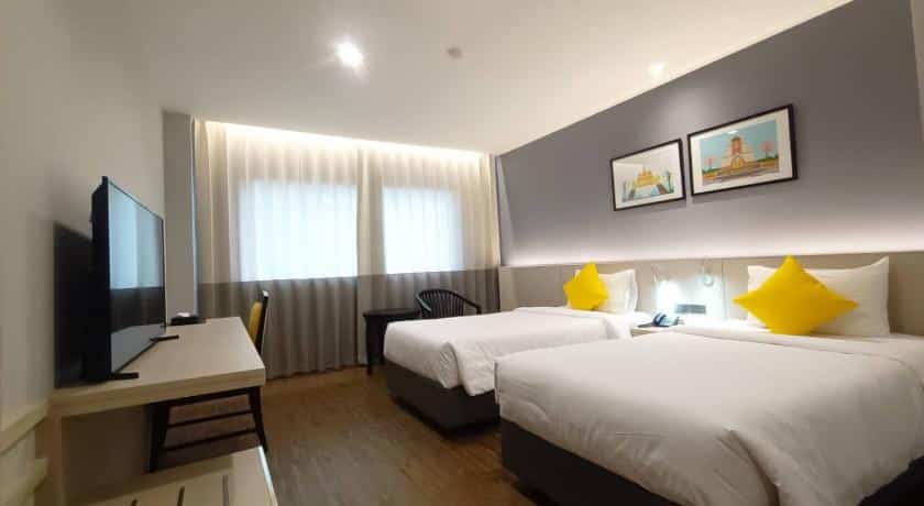 เตียงสองเตียงในห้องพักโรงแรมพร้อมหมอนสีเหลือง ที่เที่ยวขอนแก่นในเมือง