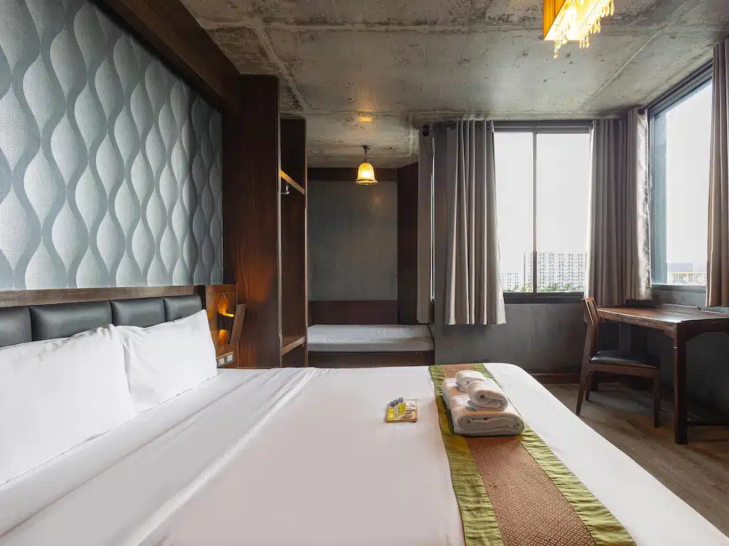 เตียงนอนสบายในห้องที่มีหน้าต่างบานใหญ่เหมาะสำหรับการเที่ยวชมสถานที่ท่องเที่ยวที่สวยงามของราชบุรี โรงแรมในเชียงใหม่