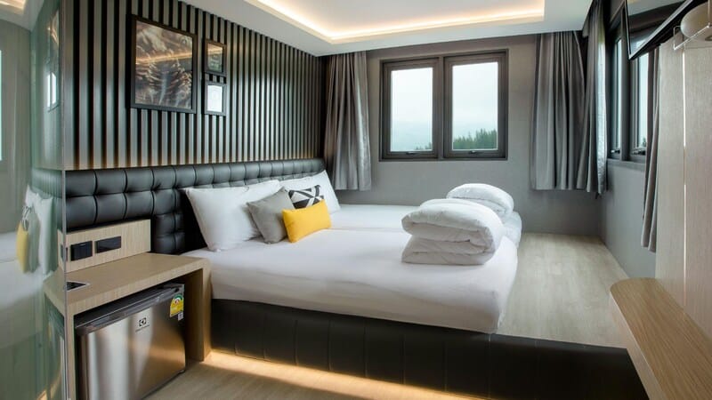 ห้องพักในโรงแรมที่มีเตียงและโต๊ะข้างเตียง ที่พักเขาค้อ ที่เที่ยวเพชรบูรณ์