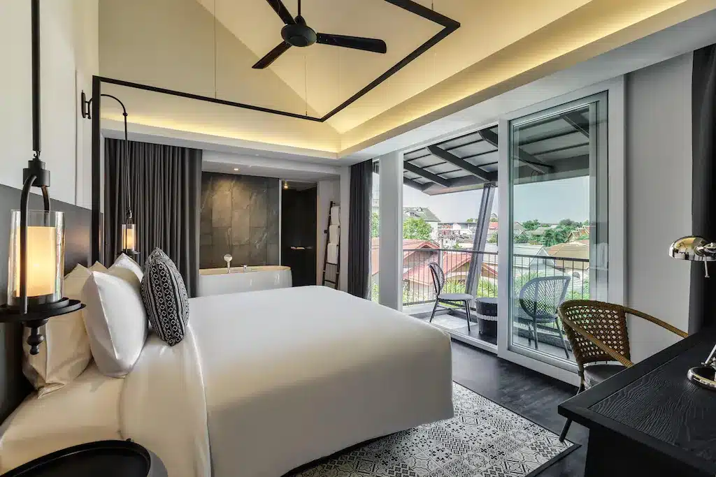 ราชบุรีที่เที่ยว: ห้องนอนพร้อมเตียงขนาดใหญ่และระเบียงเหมาะสำหรับผู้มาเยือนราชบุรีหรือต้องการเที่ยวชมสถานที่ท่องเที่ยว โรงแรมในเชียงใหม่