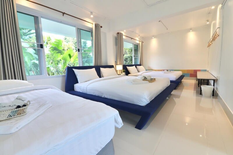 เตียงสองเตียงในห้องที่มีผ้าปูที่นอนสีขาวและหมอนสีน้ำเงิน รีสอร์ทเขาค้อ