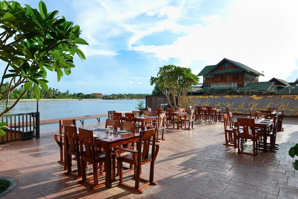ร้านอาหารที่มีโต๊ะและเก้าอี้ไม้มองเห็นวิวน้ำ ที่พักอัมพวา