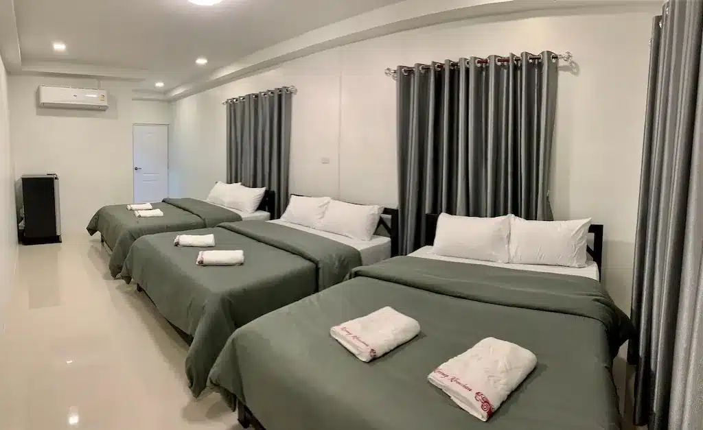 เตียงสามเตียงในห้องริมทะเลพร้อมผ้าปูที่นอนสีขาวและผ้าเช็ดตัว โรงแรมแก่งกระจาน