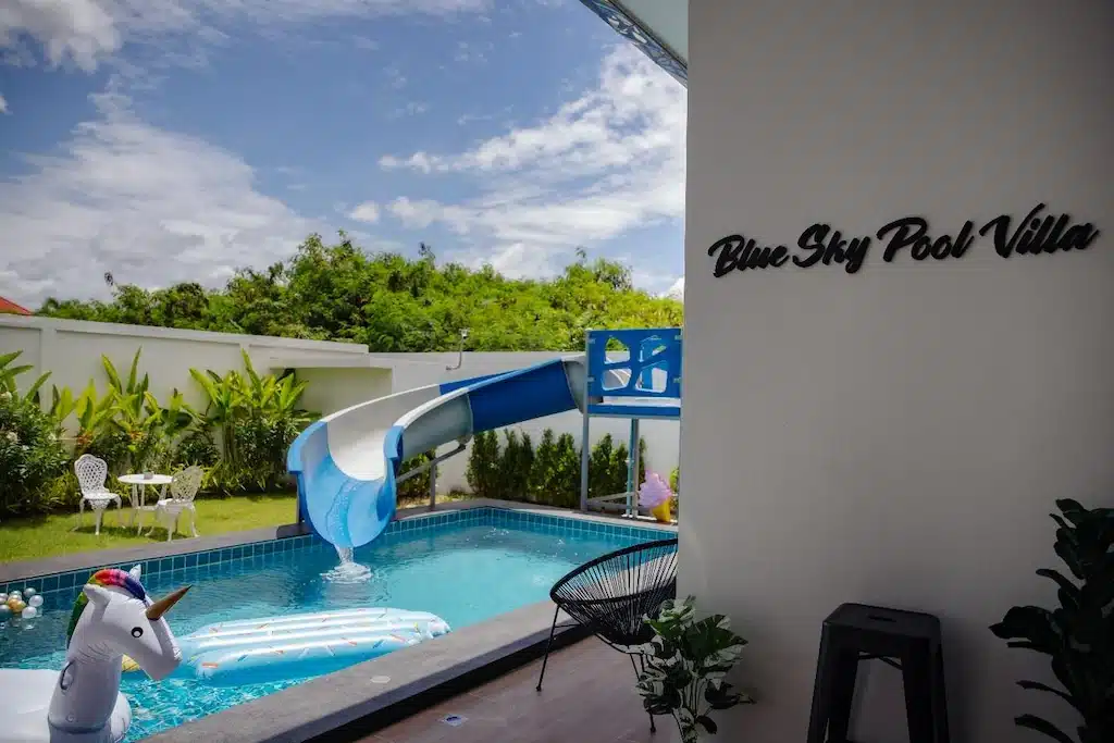 สระว่ายน้ำพร้อมสไลเดอร์และมีป้ายเขียนว่า พูลวิลล่าชะอำติดทะเล (blue sky villa)