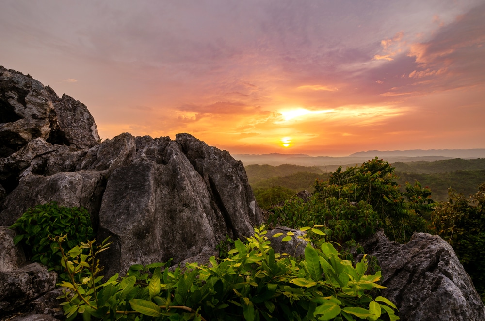พระอาทิตย์กำลังตกเหนือภูเขาในจังหวัดเพชรบูรณ์ที่สวยงาม ประเทศไทย โดยมีโขดหินเป็นฉากหลัง ที่เที่ยวเพชรบูรณ์