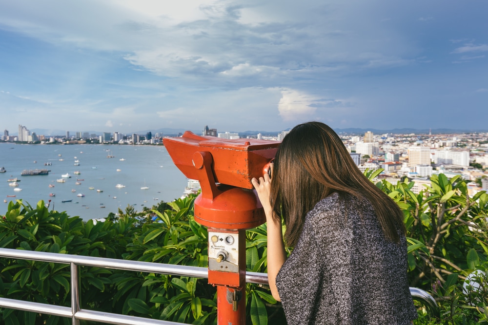 ผู้หญิงเพลิดเพลินกับทิวทัศน์เมืองพัทยาผ่านกล้องสองตา ที่เที่ยวพัทยาเข้าฟรี ที่เที่ยวพัทยาติดทะเล