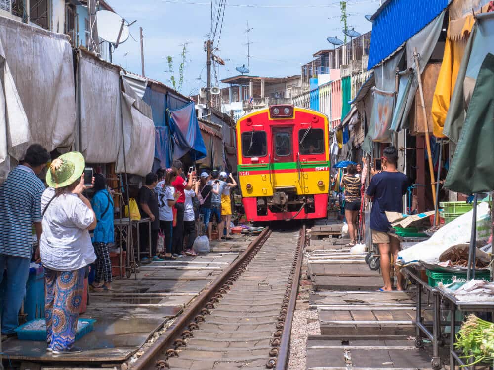 รถไฟสีแดงและเหลืองที่ ตลาดร่มหุบ เดินทางผ่านตลาดร่มห