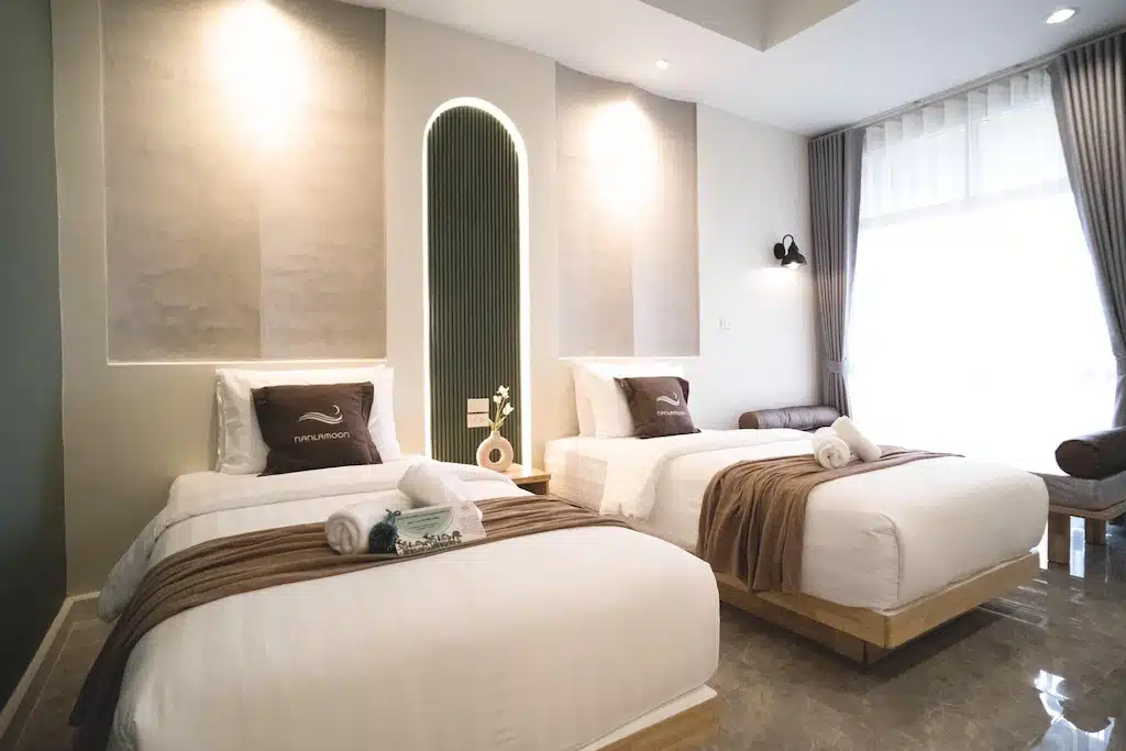 สองเตียงในห้องที่มีผ้าปูที่นอนสีขาวและผ้าเช็ดตัวในน่านที่เที่ยว ที่พักปัว