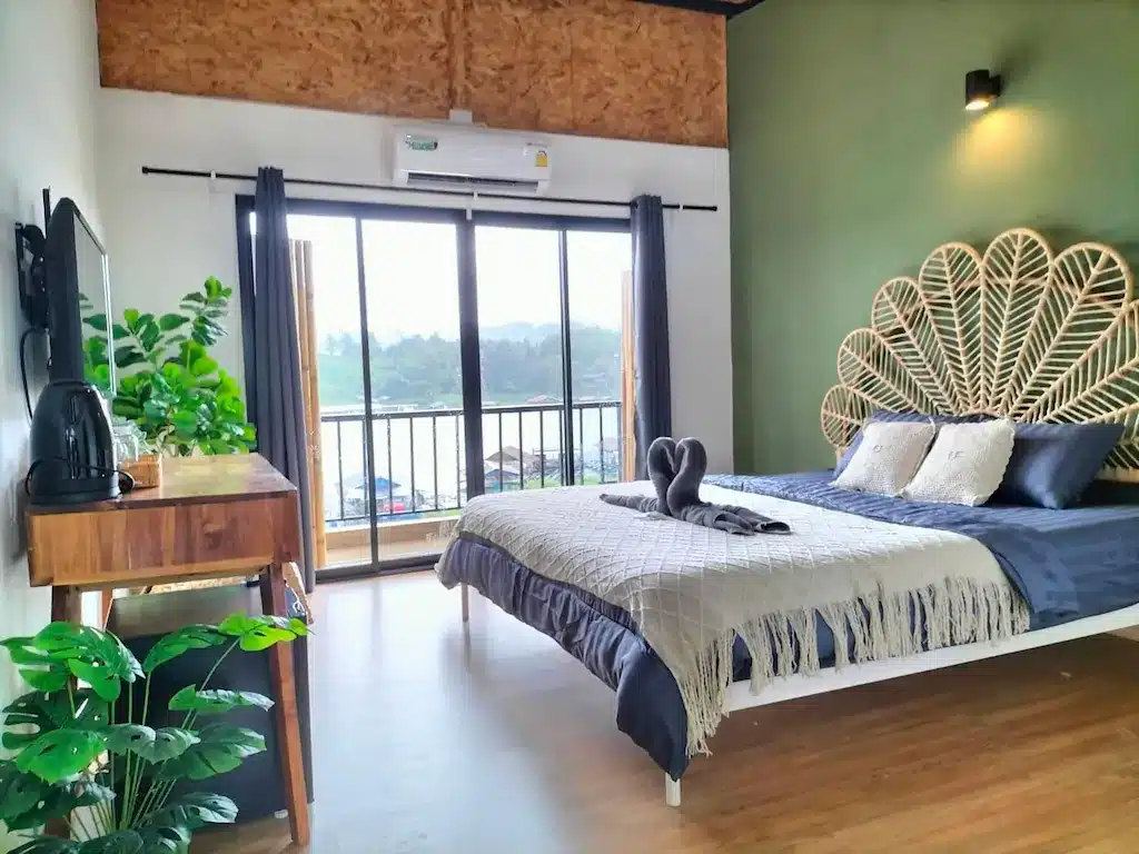 ห้องนอนที่มีผนังสีเขียวและเตียงเป็นสถานที่ท่องเที่ยวน่าน ที่พักสังขละบุรี