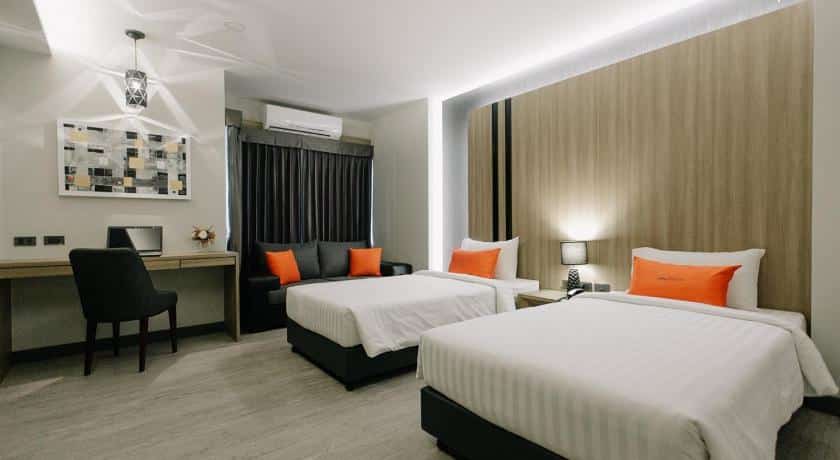 เตียงสองเตียงในห้องพักของโรงแรมตกแต่งด้วยสีส้ม โรงแรมอุบลราชธานี
