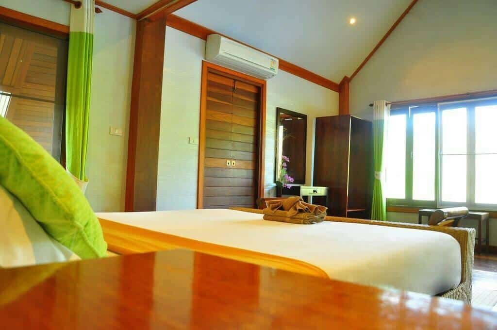ห้องนอนพร้อมเตียงและผ้าม่านสีเขียวในเที่ยวน่าน สังขละบุรีที่พัก