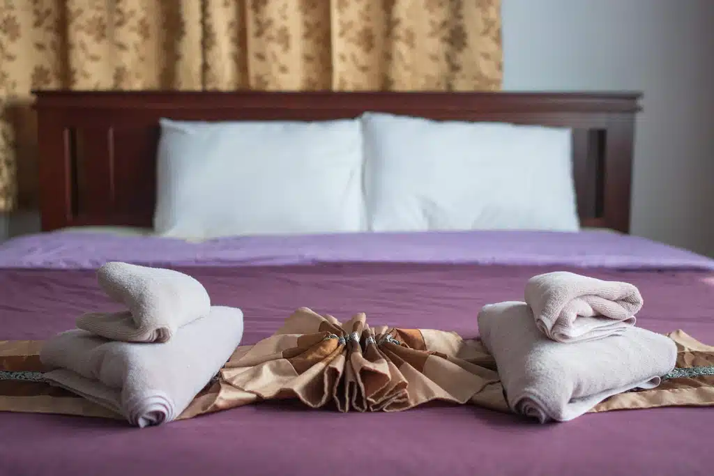 เตียงที่มีผ้าเช็ดตัวพับสองผืนอยู่ในสังขละบุรี ที่พักสังขละบุรี