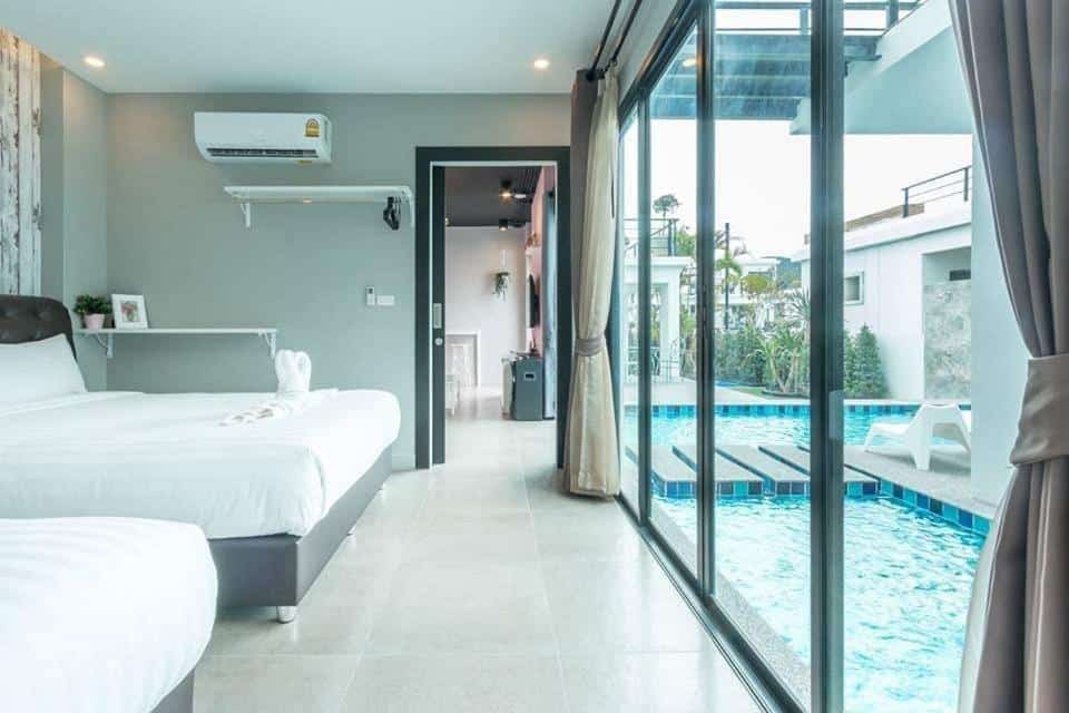 ห้องนอนที่มีประตูกระจกนำไปสู่สระว่ายน้ำในเพชรบุรีที่เที่ยว พูลวิลล่าหัวหิน