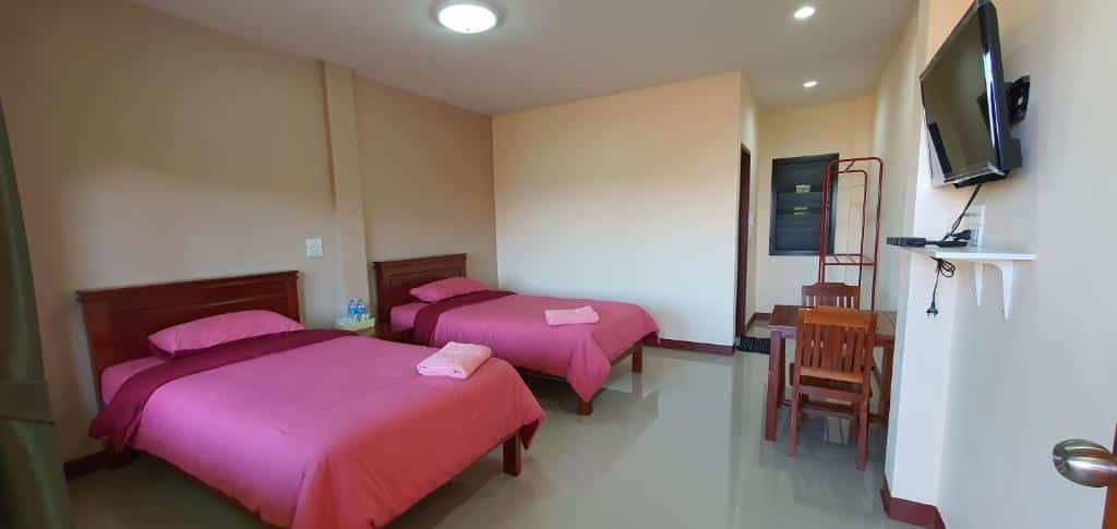 เตียง 2 เตียงในห้องที่มีผ้าปูที่นอนสีชมพูตั้งอยู่ในสถานที่ท่องเที่ยวยอดนิยม ที่พักสังขละบุรี