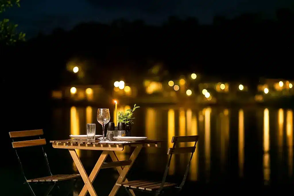เก้าอี้สองตัวและโต๊ะหน้าทะเลสาบในน่านที่เที่ยวตอนกลางคืน ที่พักสังขละบุรีราคาถูก