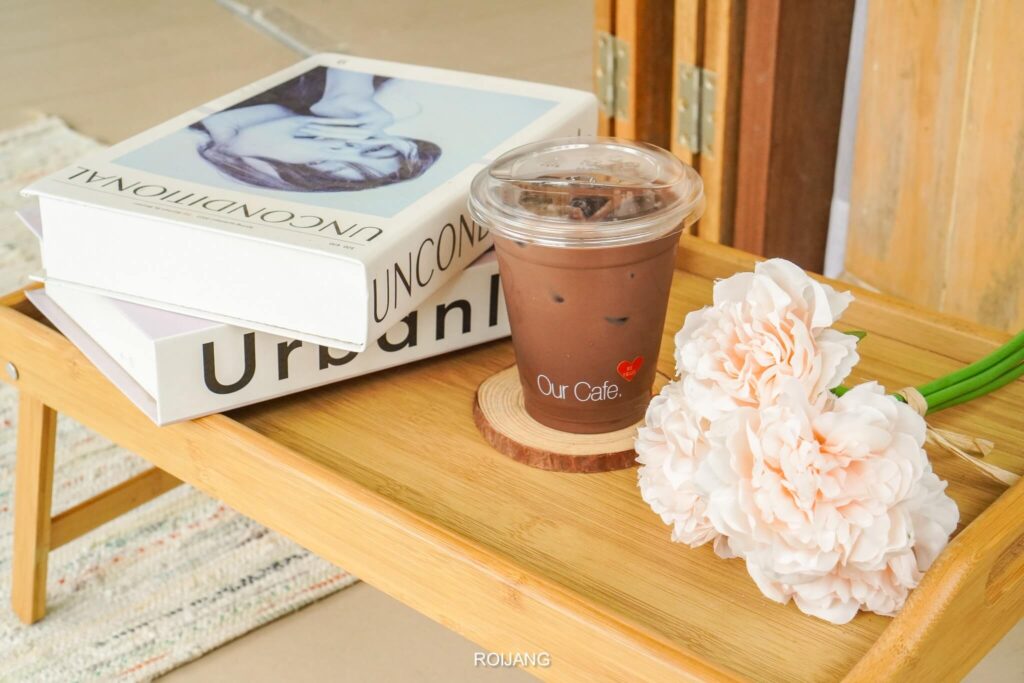 กาแฟสักแก้วบนถาดข้างหนังสือและดอกไม้ที่วัดฉลอง วัดไชยธารารามวัดฉลอง