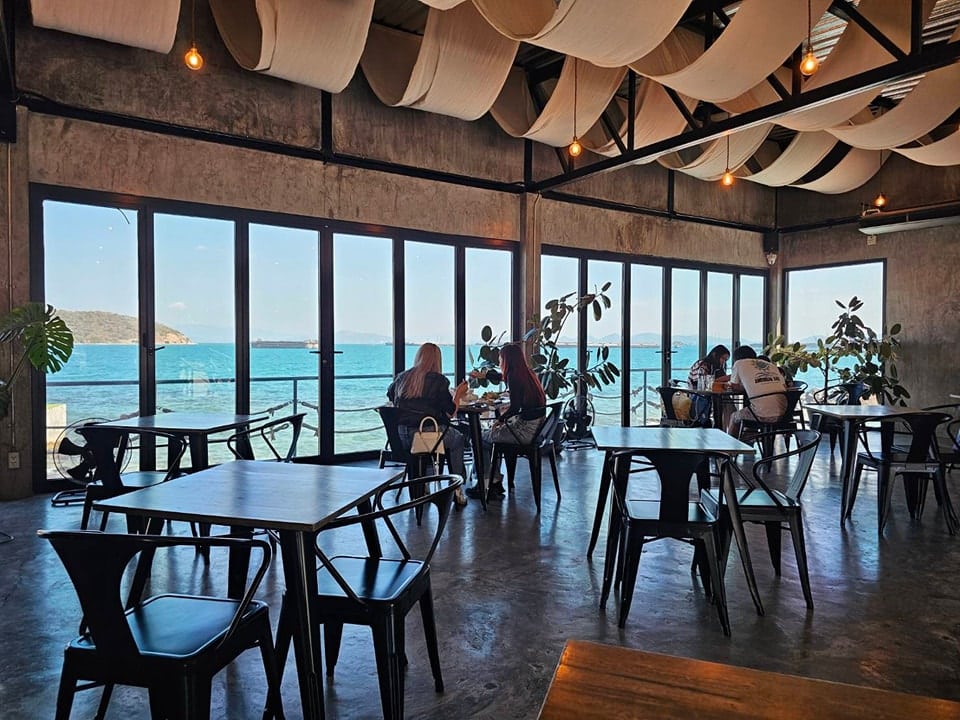 ร้านอาหารพร้อมโต๊ะและเก้าอี้ที่มองเห็นวิวทะเลในบรรยากาศอันเงียบสงบ เกาะสีชัง