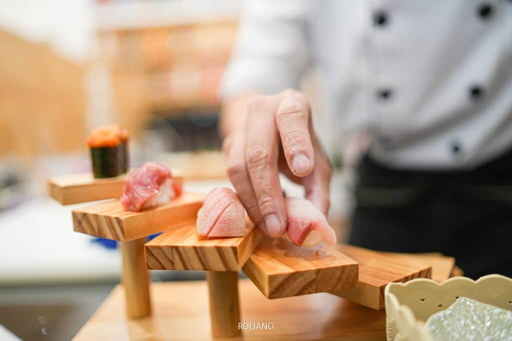 พ่อครัวกำลังเตรียมซูชิอย่างเชี่ยวชาญบน ร้านอาหารญี่ปุ่นภูเก็ต กระดานไม้ที่ร้านอาหารญี่ปุ่นชื่อดังในภูเก็ต