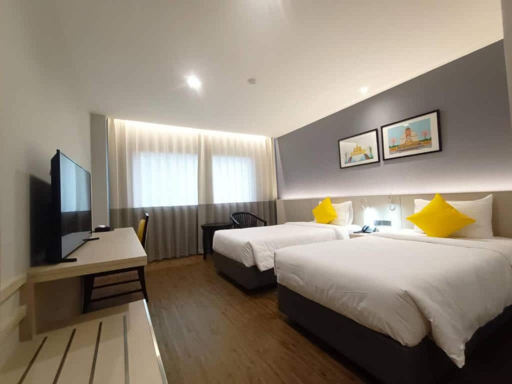 เตียงสองเตียงในห้องพักของโรงแรมพร้อมหมอนสีเหลืองที่ภูผาม่าน ที่พักภูผาม่าน