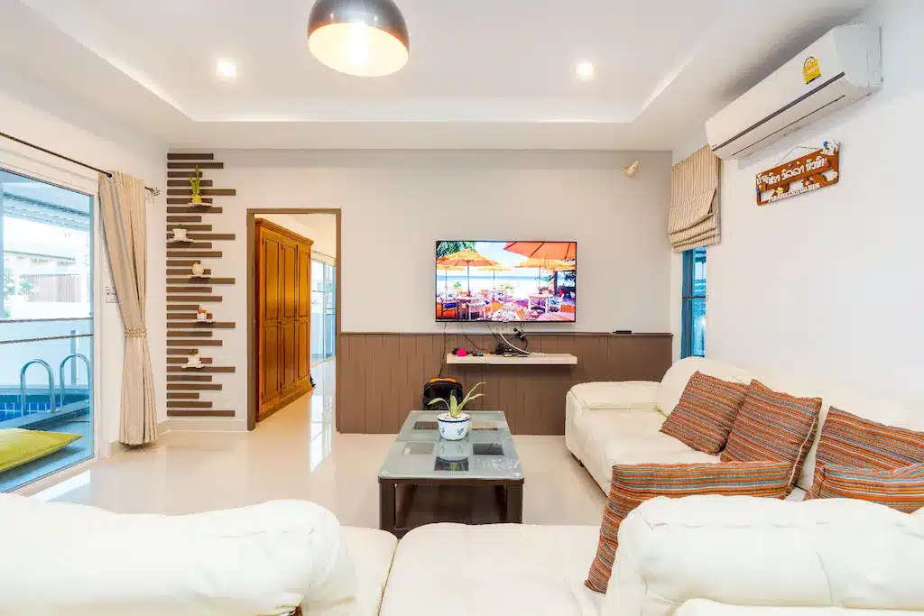 ห้องนั่งเล่นพร้อมโซฟาสีขาวและทีวีในบ้านพักตากอากาศริมชายหาด บ้านพักติดทะเลหัวหิน