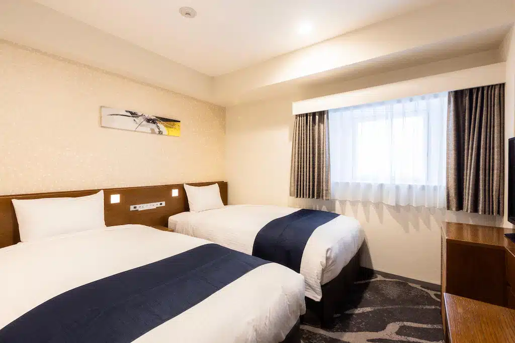 ห้องพักในโรงแรมที่มีเตียง 2 เตียงและโทรทัศน์ในข้อมูลท่องเที่ยวในญี่ปุ่น ที่เที่ยวญี่ปุ่น