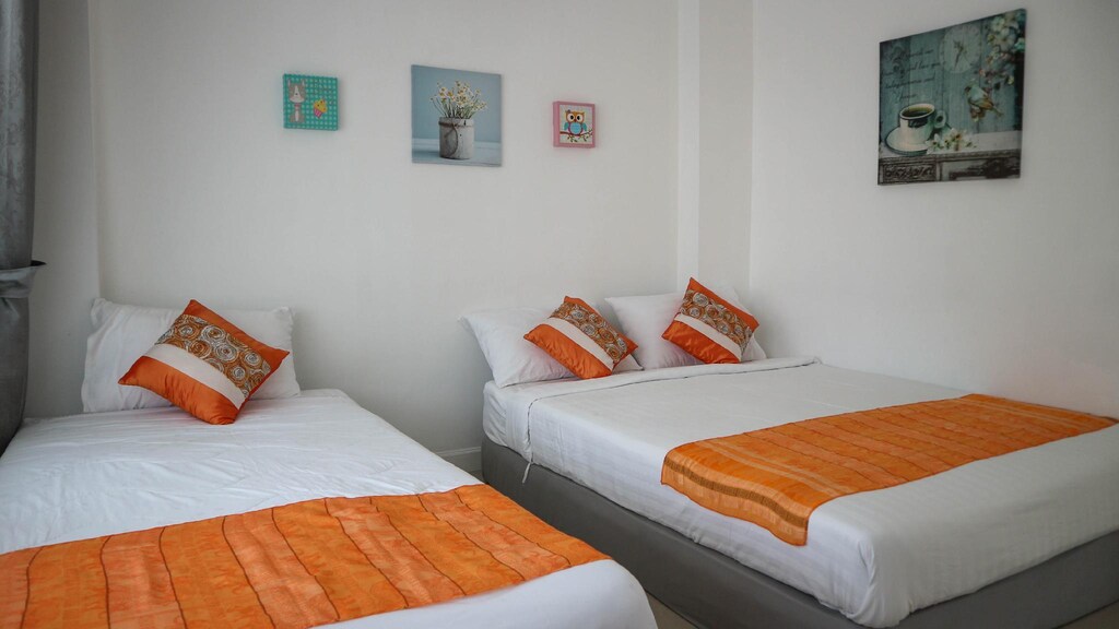 เตียงสองเตียงพร้อมชุดเครื่องนอนสีส้มและสีขาวในห้องในวิลล่าหัวหิน พูลวิลล่าหัวหิน