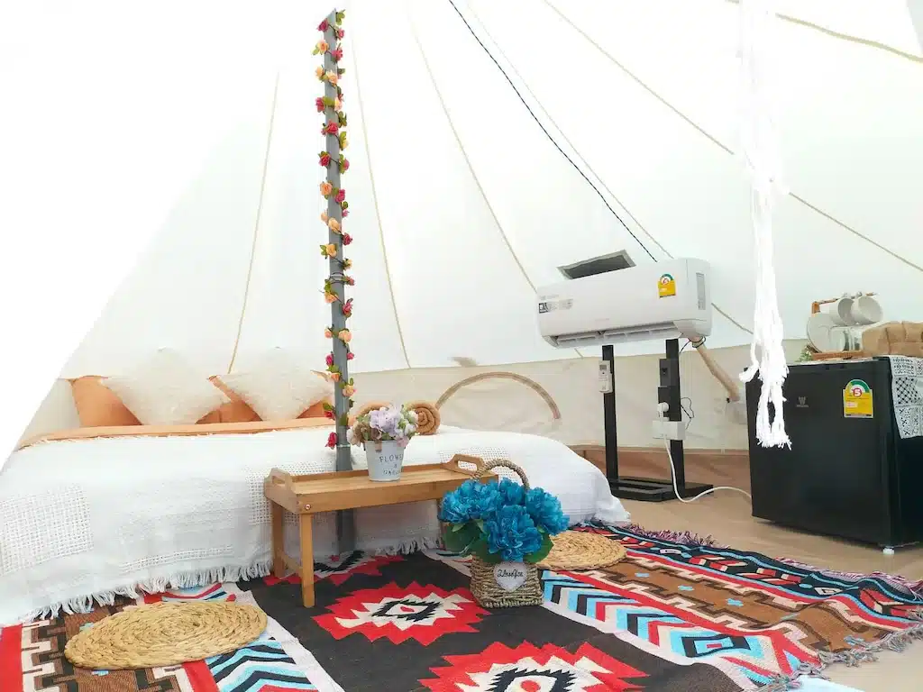 ห้องในเต็นท์พร้อมเตียงและโต๊ะข้างเตียงตั้งอยู่ในพื้นที่ท่องเที่ยวน่า ที่พักสังขละบุรี น