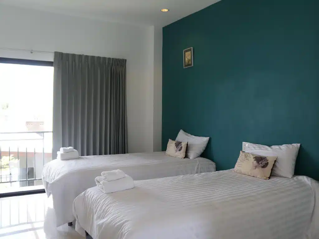 เตียงสองเตียงในห้องที่มีผนังสีเขียวตั้งอยู่ใน ที่พักภูผาม่าน คุณสมบัติของภูผาม่าน