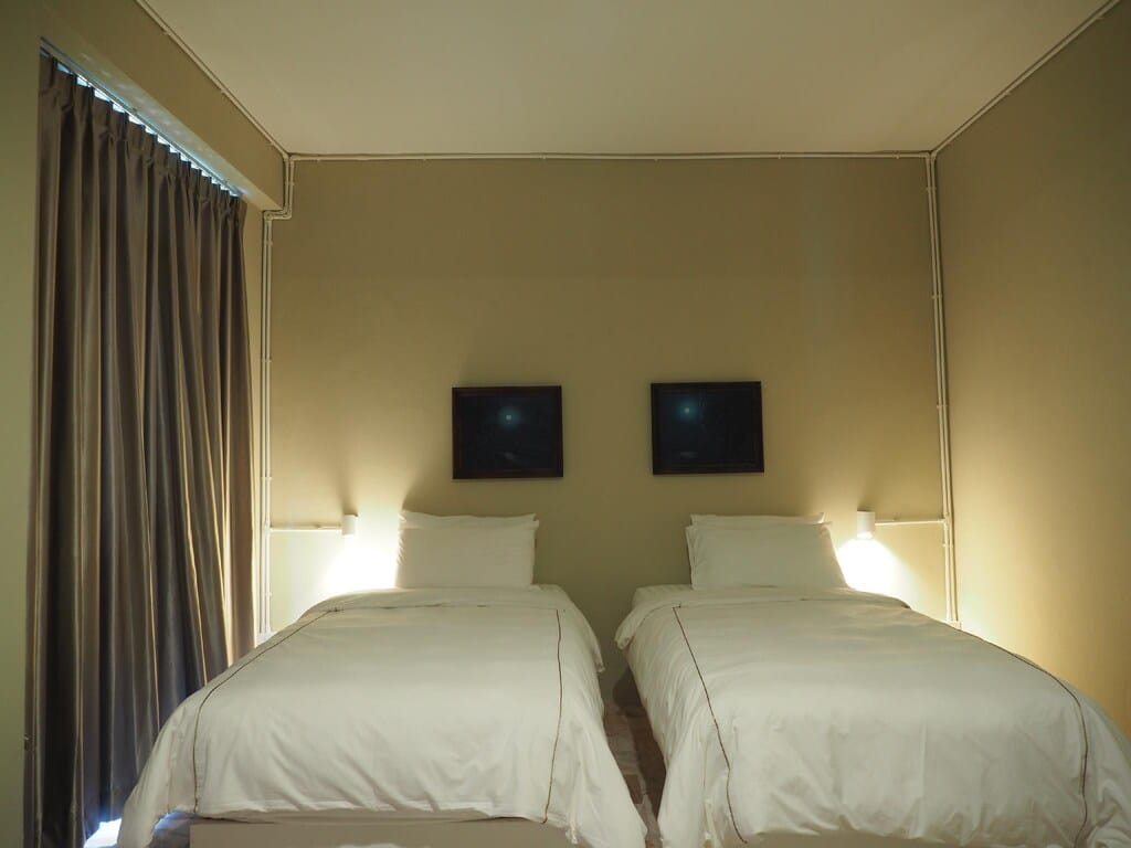 เตียงสองเตียงในห้องที่มีผ้าปูที่นอนสีขาวสะอาด เมืองโบราณสมุทรปราการ