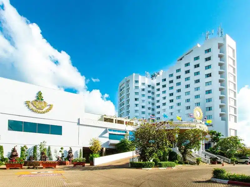 โรงแรมสีขาวมีต้นไม้อยู่ด้านหน้า เหมาะสำหรับนักท่องเที่ยวที่ต้องการพักผ่อนในจังหวัดสุรินทร์