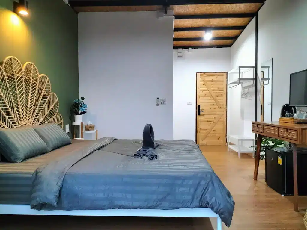 เตียงในห้องที่มีผนังสีเขียวและพื้นไม้ตั้งอยู่ในจุดท่องเที่ยวน่าน ที่พักสังขละบุรี
