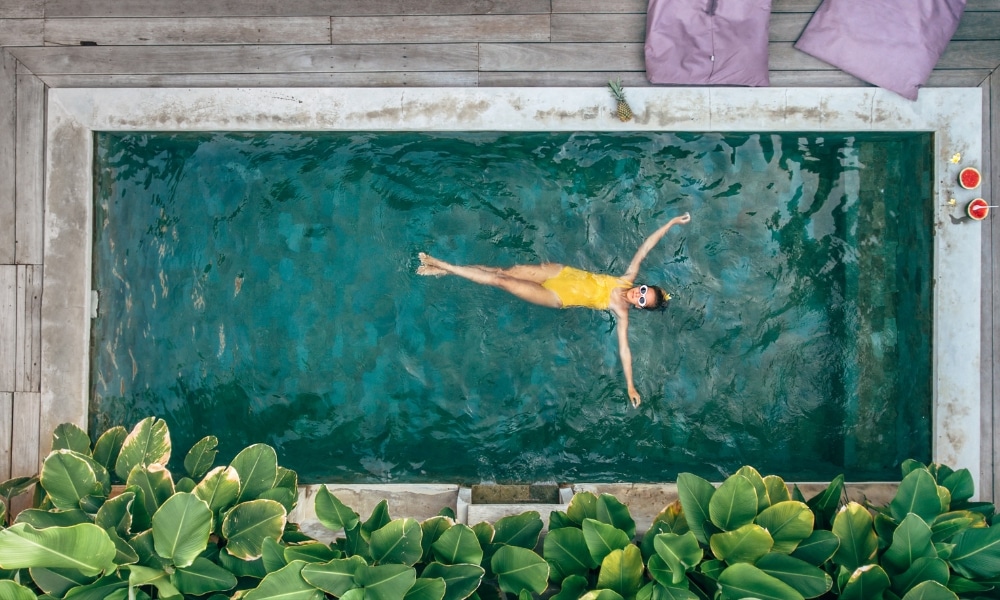 ผู้หญิงในชุดว่ายน้ำสีเหลืองลอยอยู่ในสระน้ำที่พูลวิลล่าหัวหินติดทะเล บ้านพักติดทะเลหัวหิน