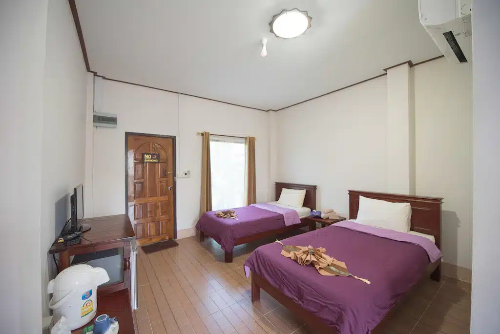 สองเตียงในห้องที่มีผ้ ที่พักสังขละบุรี ปูที่นอนสีม่วงที่สังขละบุรี
