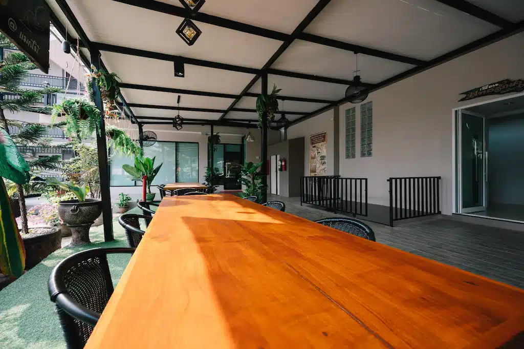 โต๊ะและเก้าอี้ไม้บนลานบ้านในรีสอร์ทแสนผ่อนคลายในจังหวัดสระบุรี ที่พักสังขละบุรี