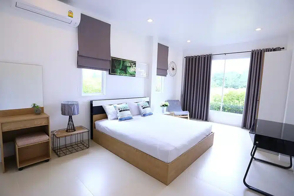 ห้องนอนสีขาวพร้อมเตียงและโต๊ะในเพชรบุรี ประเทศไทย pool villa หัวหิน