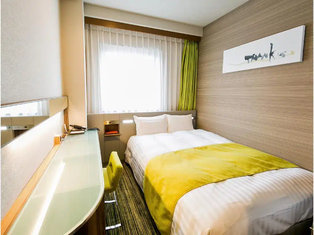 เตียงพร้อมผ้าห่มสีเหลืองในห้องพักในจังหวัดราชบุรีประเทศไทย เที่ยวญี่ปุ่น
