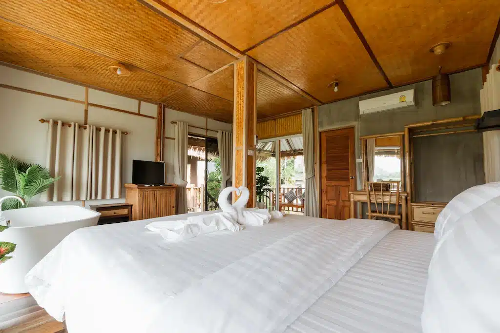 ห้องนอนเพดานไม้และเตียงสีขาว ตั้งอยู่ในเที่ยวน่าน ที่พักปัว