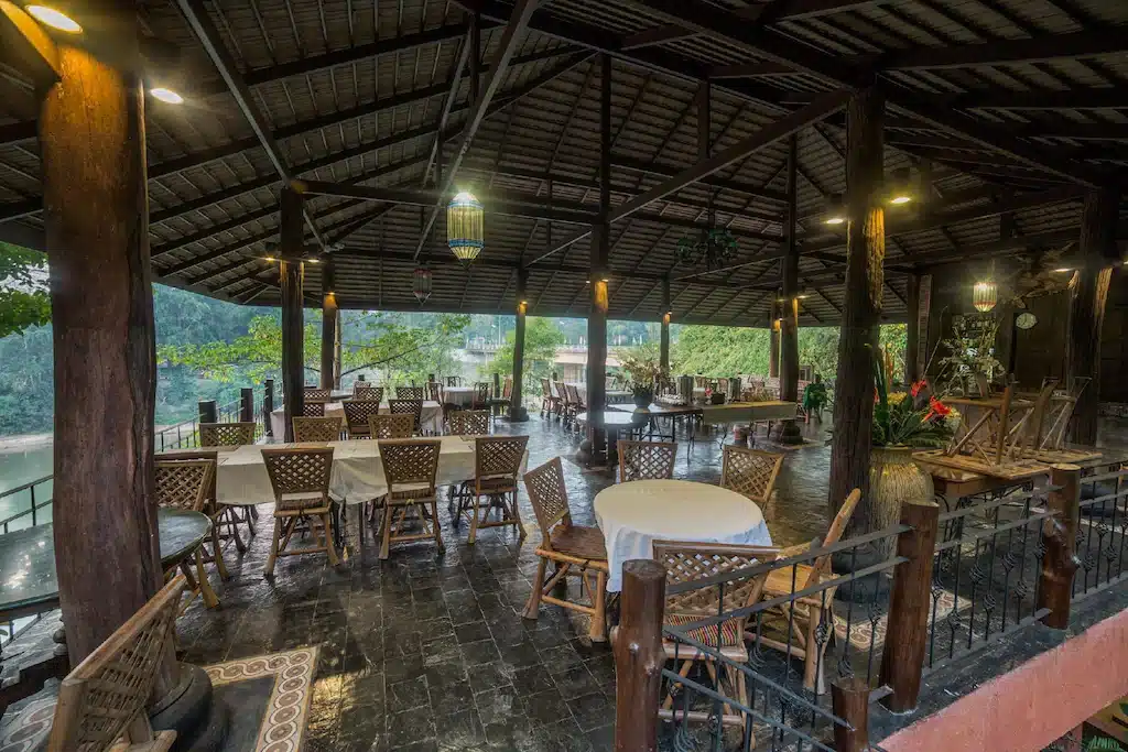 ร้านอาหารที่มีโต๊ะและเก้าอี้อยู่กลางพื้นที่ป่า น่านที่เที่ยว ที่พักสังขละบุรีราคาถูก