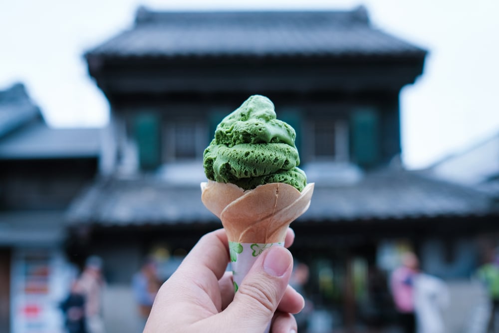 คนถือโคนไอศกรีมสีเขียวหน้าอาคารเอเชีย สถานที่ท่องเที่ยวยอดนิยมในญี่ปุ่น เที่ยวญี่ปุ่นด้วยตัวเอง