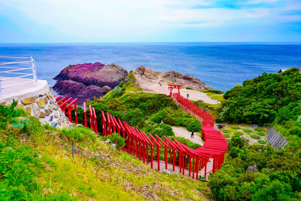 บันไดสีแดงทอดขึ้นสู่หน้าผามองเห็นทะเลในเที่ยวราชบุรี ที่เที่ยวญี่ปุ่น