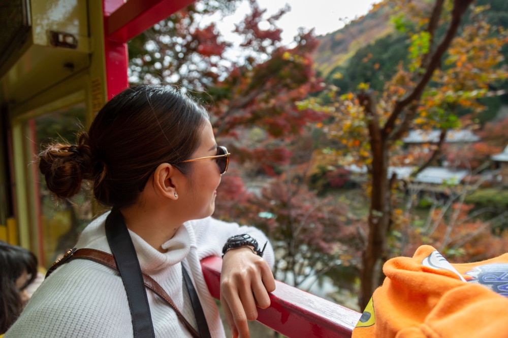 ผู้หญิงมองออกไปนอกหน้าต่างรถไฟระหว่างการเดินทางสบายๆ เที่ยวญี่ปุ่น