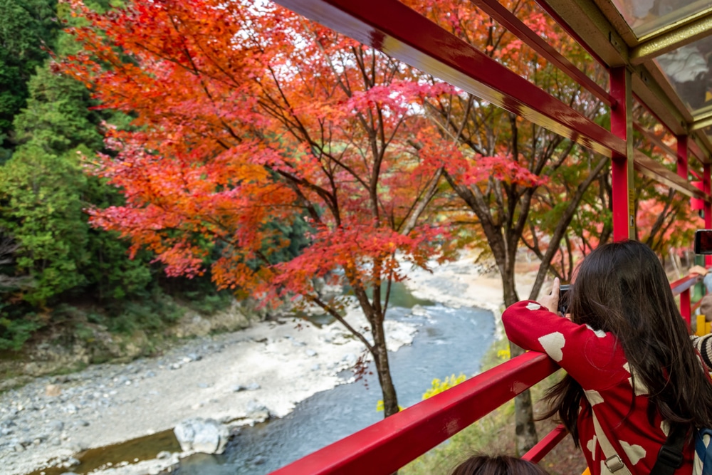 กลุ่มคนนั่งบนราวจับริมแม่น้ำที่สถานที่ท่องเที่ยวราชบุรี  เที่ยวญี่ปุ่น