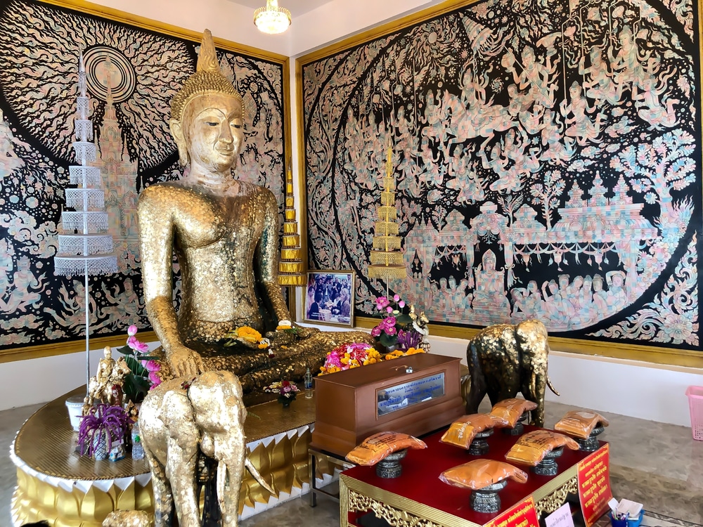 พระพุทธรูปทองคำยืนประดิษฐานอยู่หน้าภาพวาด ณ แหล่งท่องเที่ยวรา ที่เที่ยวสัตหีบ ชบุรีอันสวยงาม